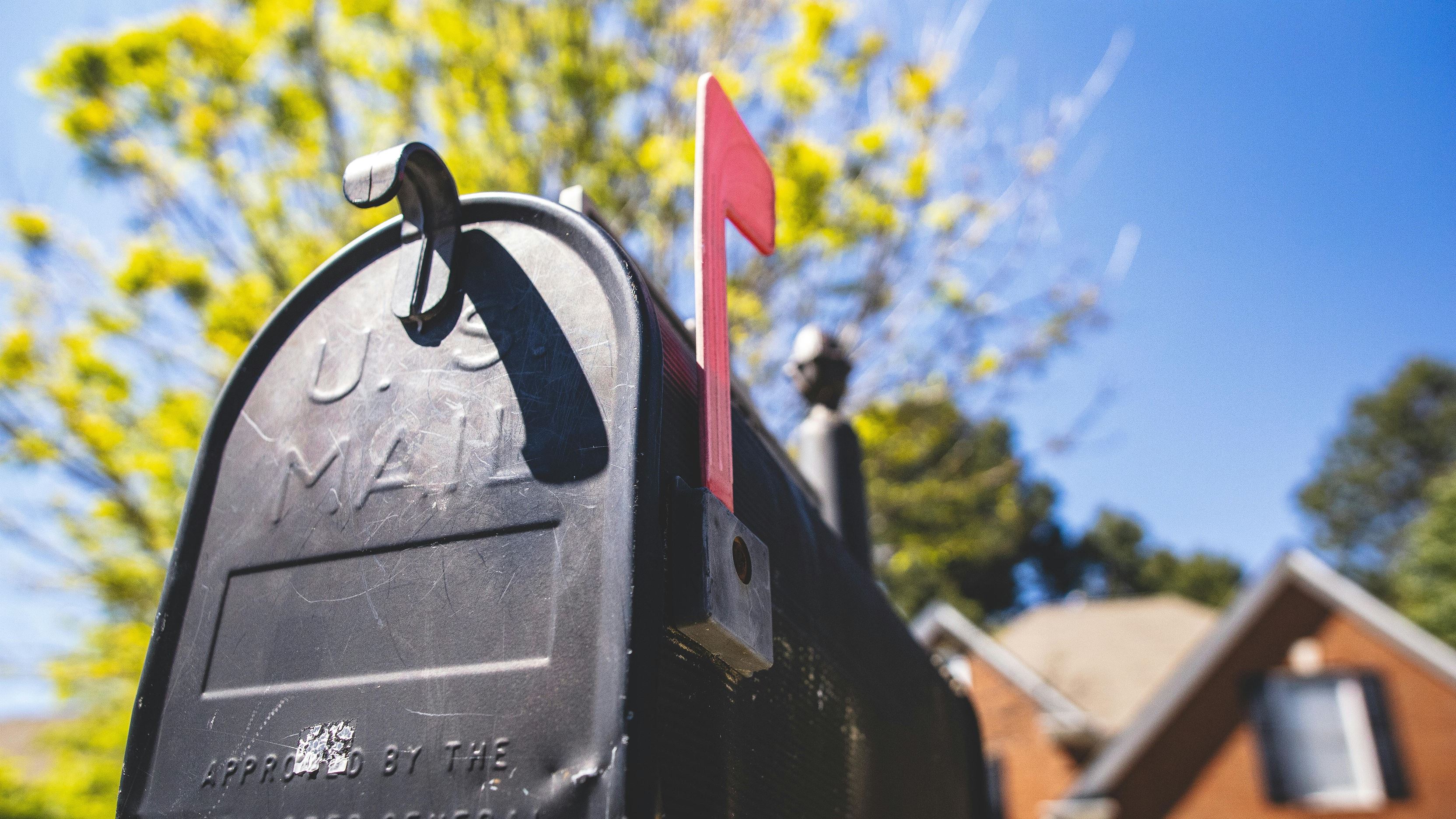 Mailbox with its flag up in front of a defocused brick house