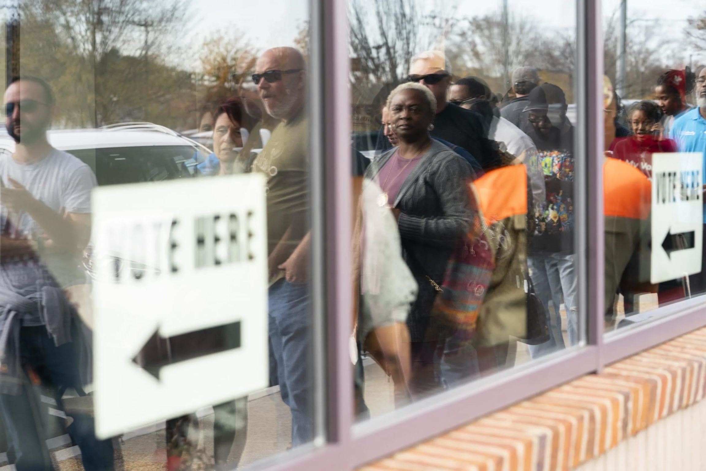 Reflection on window of voters waiting in line to vote